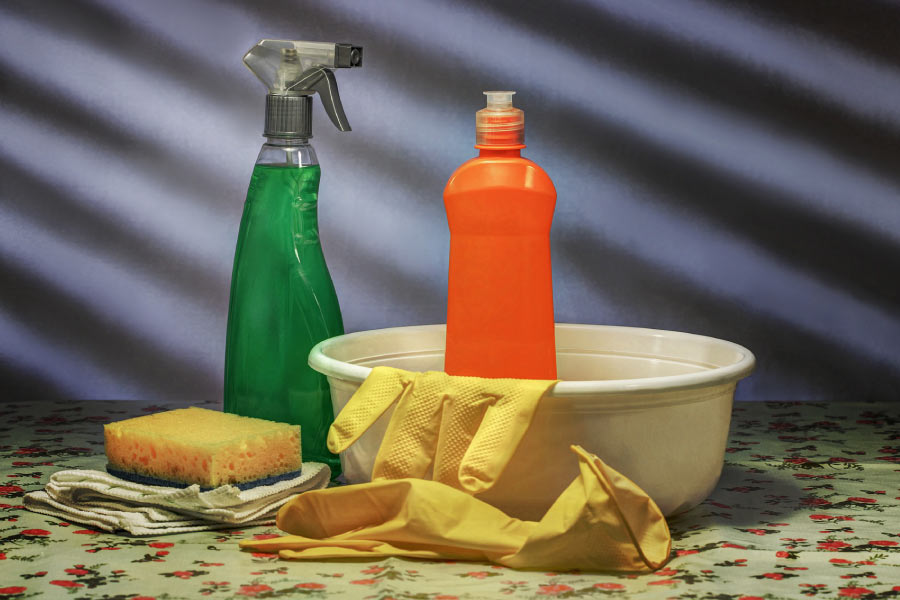 Photo of cleaning supplies including bowl, sponge, rubber gloves, spray bottle and soap