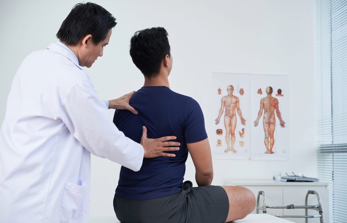 Therapist working with a male patient and assessing muscle use in the back