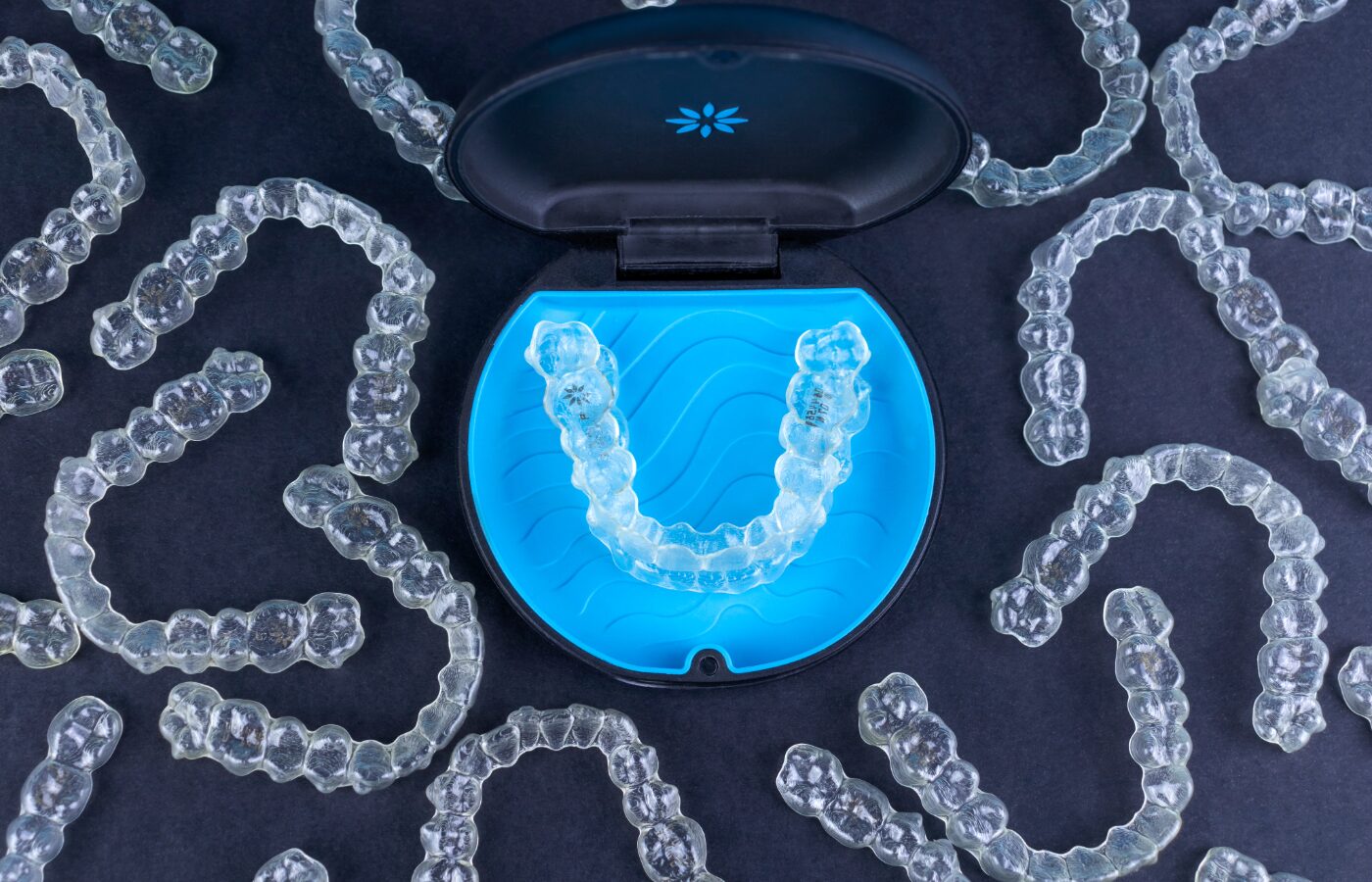 Clear expansive aligners on a blue backdrop that produce a pattern with a black case in the middle