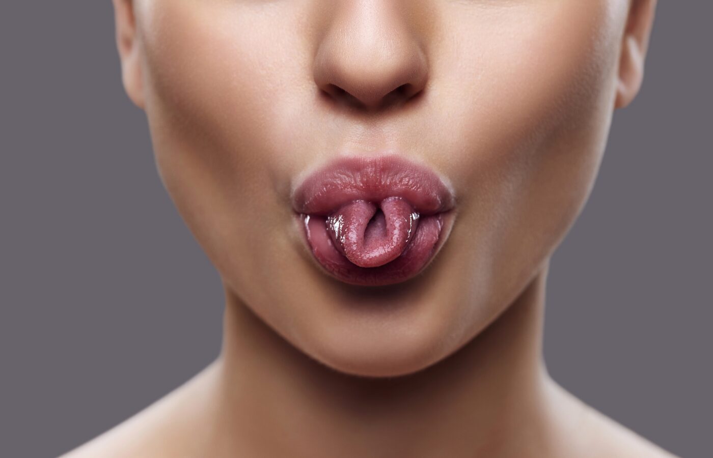 the bottom half of a woman’s face with her tongue rolled into a taco