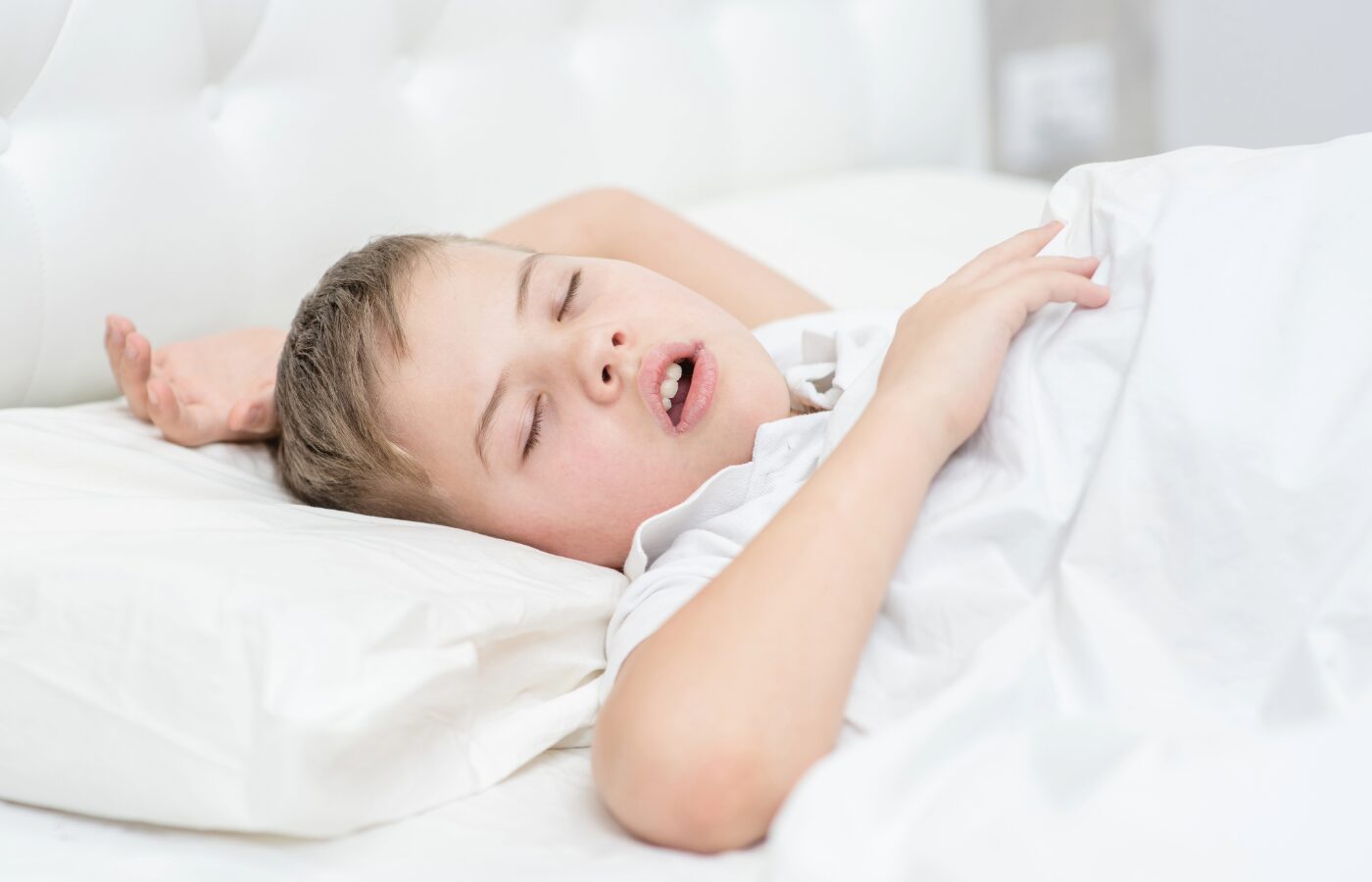 image of young blonde boy in a white bed breathing with his mouth open signalling sleep-disordered breathing